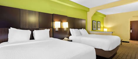 A hotel room with two beds, a green accent wall, and a patterned carpet.