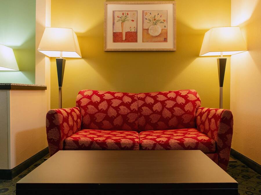 A red sofa with a floral pattern, two floor lamps, and a framed artwork on the wall.