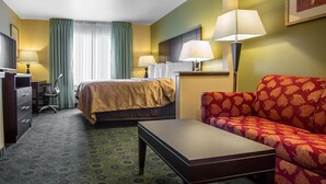 A hotel room with a bed, a sofa, a desk, and two lamps. - Quality Inn & Suites Bloomington I-55 and I-74 (Bloomington)