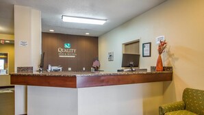 A hotel reception desk with a sign reading "Quality Inn & Suites by Choice Hotels," an American flag, and a "Manager on Duty" sign. - Quality Inn & Suites Bloomington I-55 and I-74 (Bloomington)