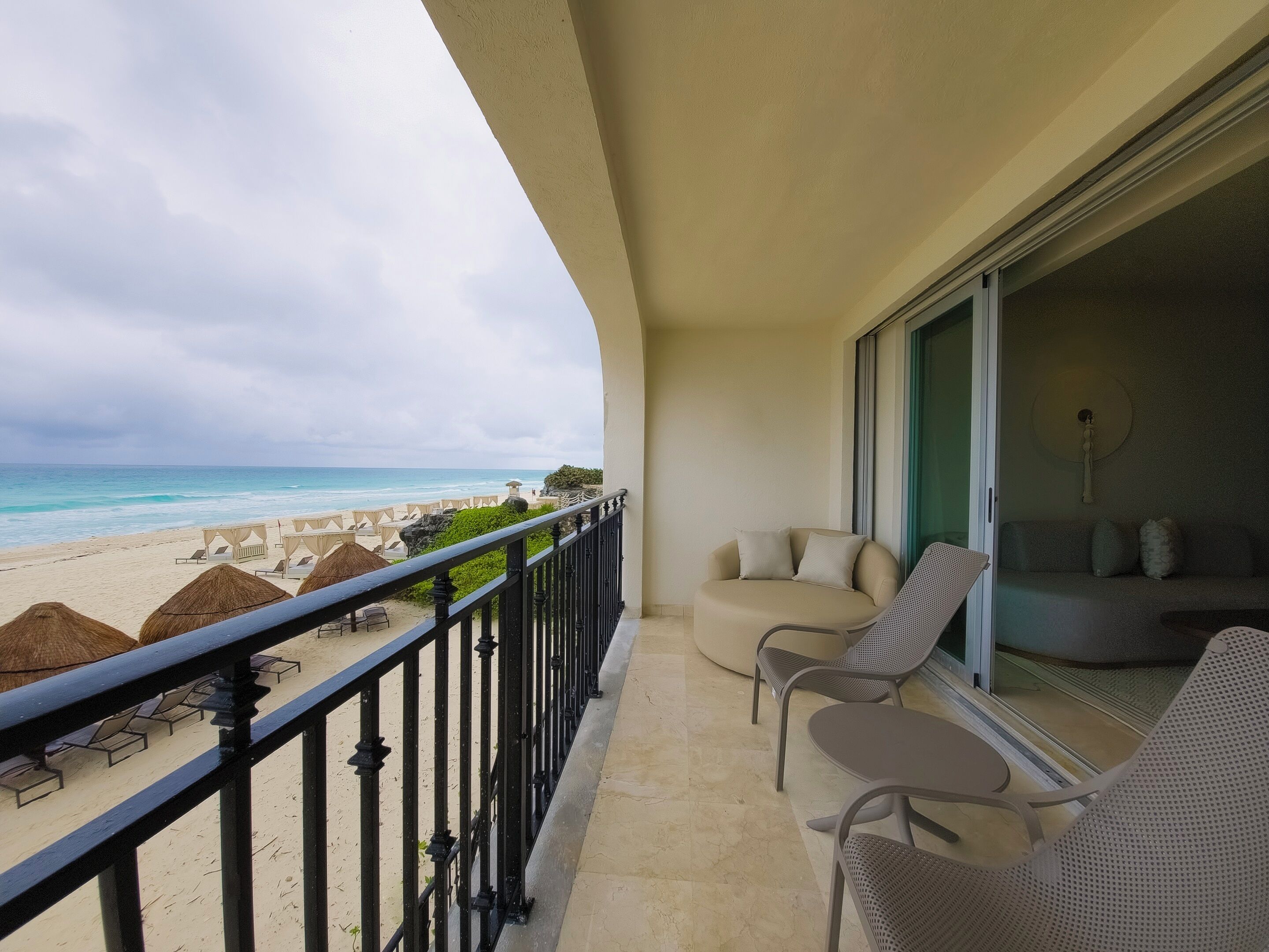 A balcony with a view of the beach, lounge chairs, and a sofa.
