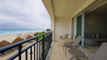 A balcony with a view of the beach, lounge chairs, and a sofa.