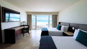 Habitación de hotel con dos camas, un escritorio, televisión y vista al océano.