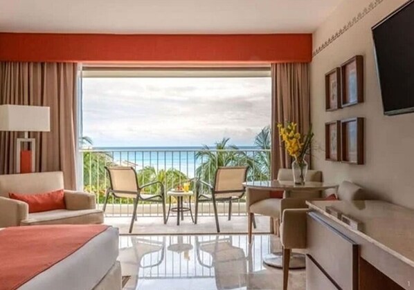 Enjoy a sea view from the balcony, featuring a comfortable bed, seating area, and flat-screen TV.