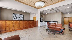 A lobby with a reception desk, leather seating, a tiled floor, and a kitchen area in the background. - Super 8 by Wyndham Longview/North (Longview)