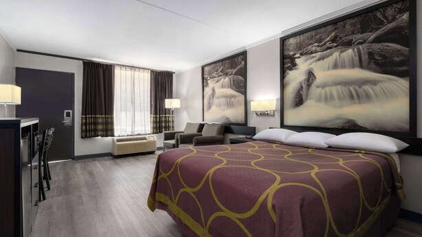 A hotel room with a large bed, a desk, a chair, a TV, and a window with curtains. - Super 8 by Wyndham Longview/North (Longview)