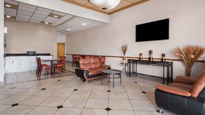 A spacious lobby with a modern design, featuring a seating area with leather sofas, a coffee table, and a dining area with chairs and a table. - Super 8 by Wyndham Longview/North (Longview)