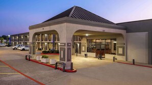 A modern hotel entrance with a covered waiting area, multiple entry points, and a parking lot. - Super 8 by Wyndham Longview/North (Longview)