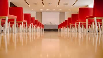 A conference room with rows of red chairs and a podium at the front.