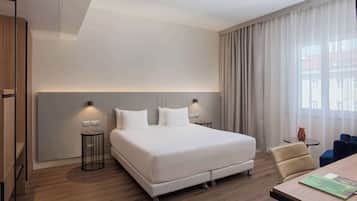 A modern hotel room with a large bed, bedside lamps, a desk, and a chair.