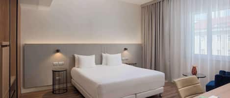 Una habitación de hotel moderna con una cama grande, lámparas de noche, un escritorio y una silla.