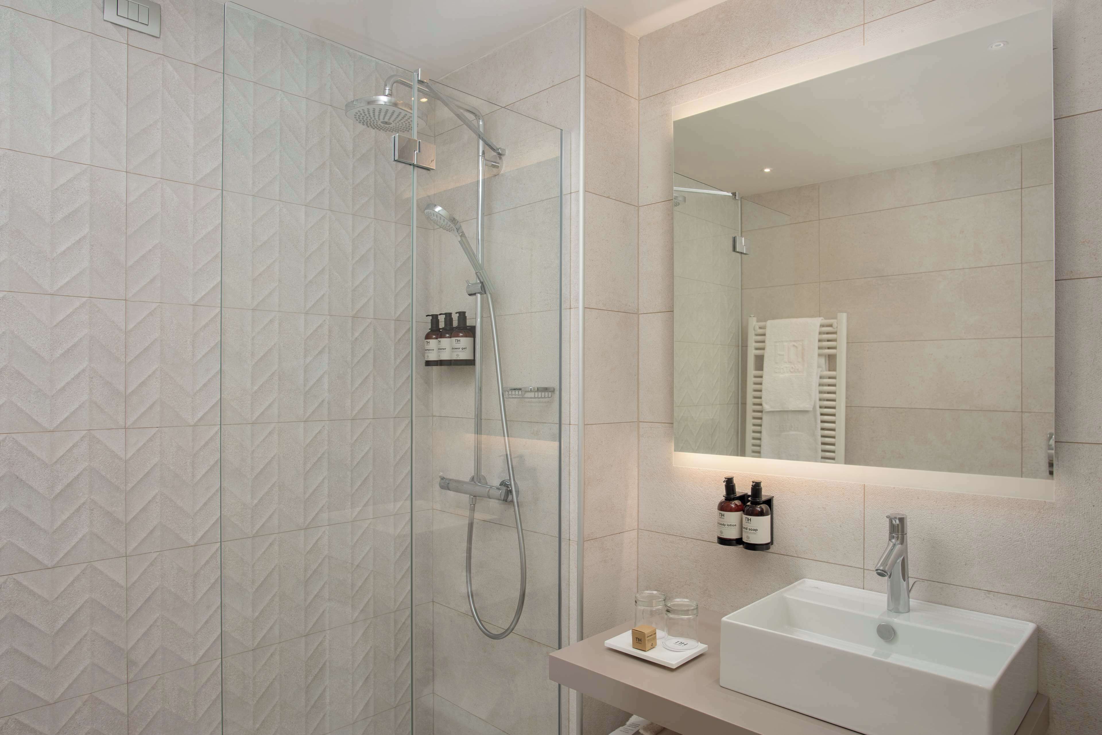 A modern bathroom with a glass-enclosed shower, a white sink, and a mirror above it.
