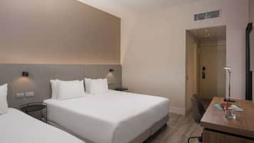 Habitación de hotel con dos camas, un escritorio y una silla.