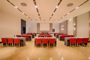 Ein Konferenzraum mit mehreren Tischen und Stühlen, ausgestattet mit Projektoren und Bildschirmen.
