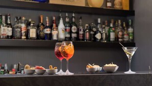 A bar area with various bottles and glasses, including two cocktails and a martini. - NH Trieste (Trieste)