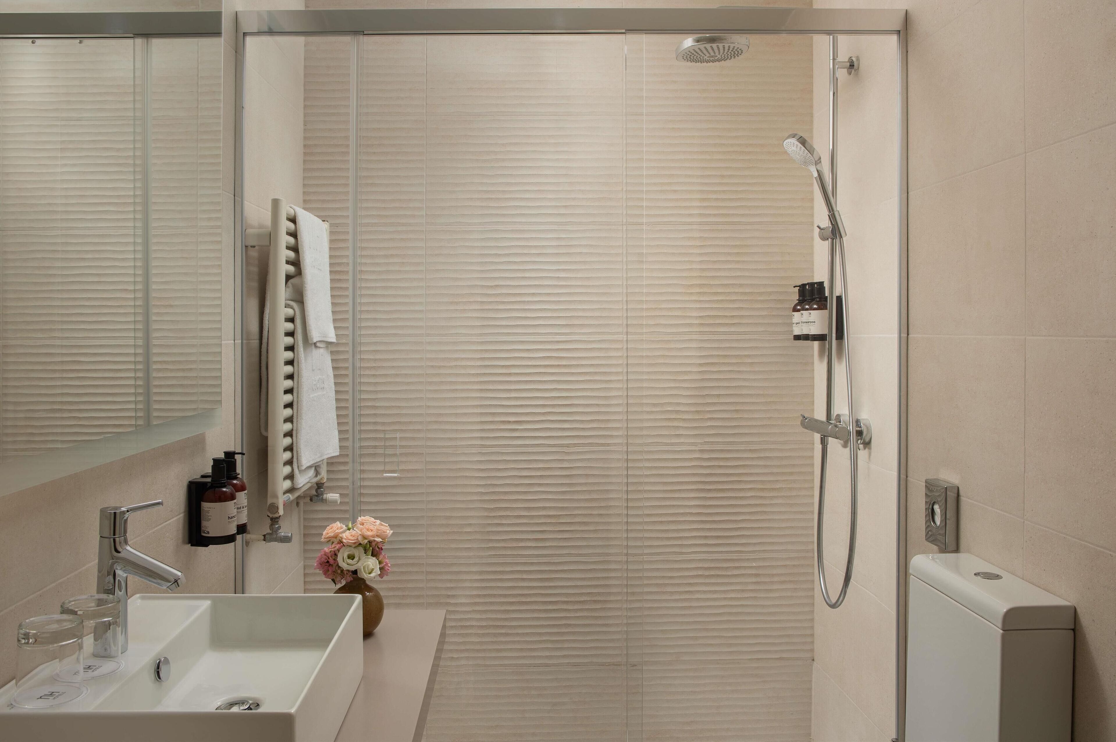 Une salle de bain moderne avec une douche, un lavabo et un miroir.