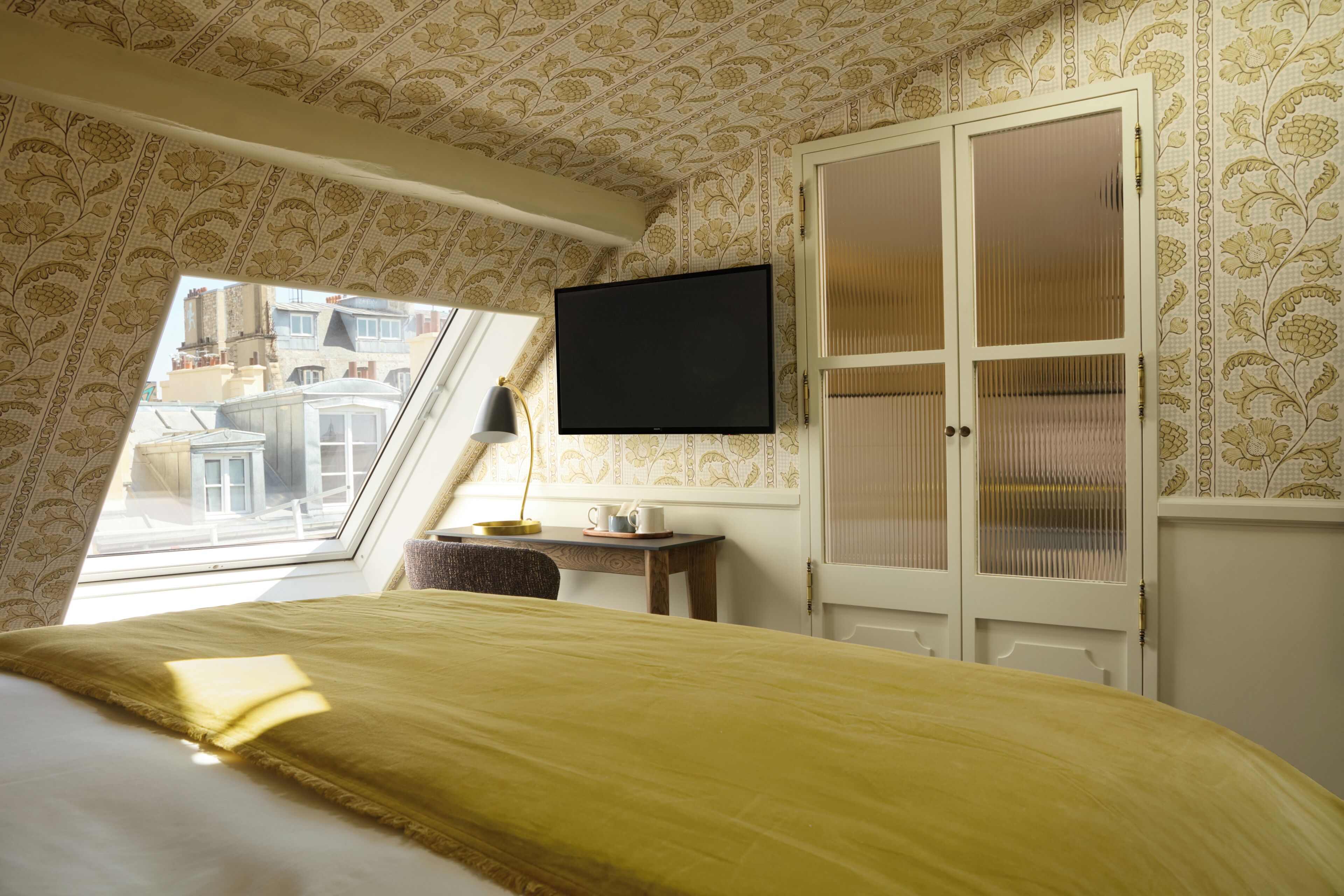 Quarto com cama, televisão, escrivaninha e guarda-roupa.