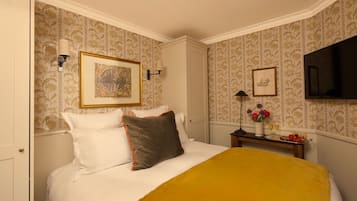 A hotel room with a bed, a nightstand, a TV, and a framed picture on the wall.