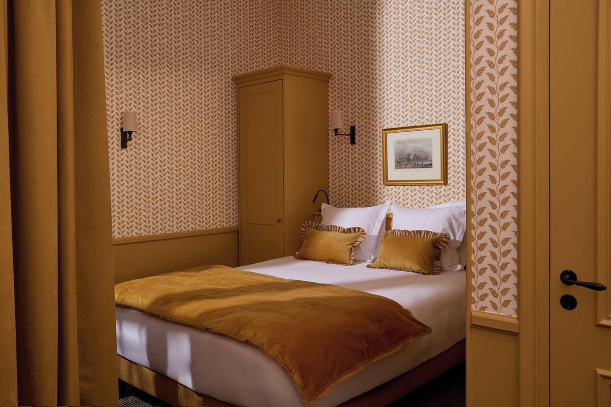 A bedroom with a bed, a wardrobe, a nightstand, and a framed picture on the wall.