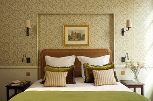 A neatly made bed with a green bedspread, two pillows, and a framed picture on the headboard.