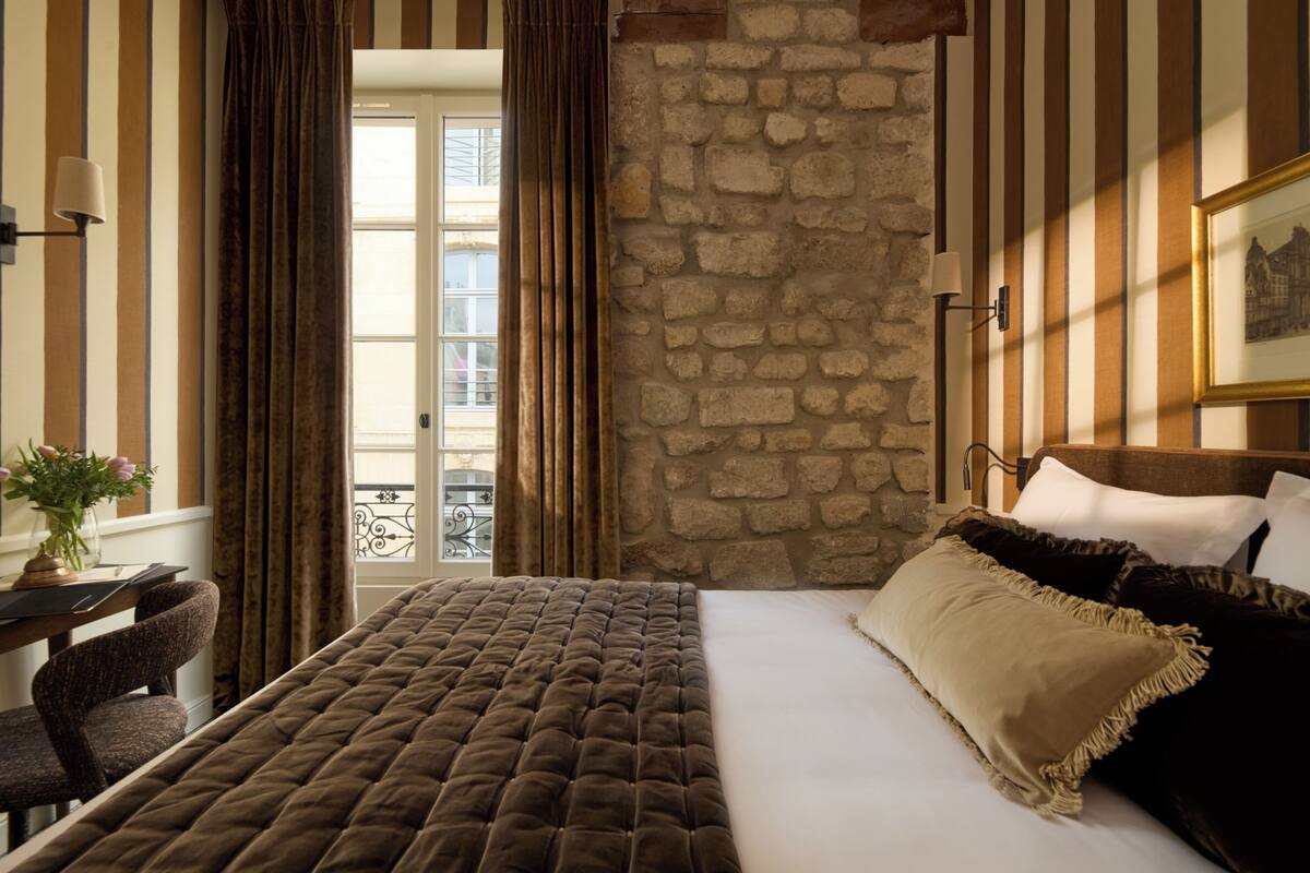 A room with a bed, a desk, and a stone wall.