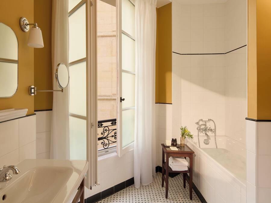 Un baño con bañera, lavabo, espejo y ventana con cortina.