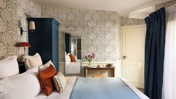 A hotel room with a bed, a nightstand, a mirror, a desk, and a door.