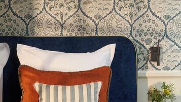 Un lit avec une tête de lit bleue, des oreillers blancs et à rayures, et une couverture bleue.