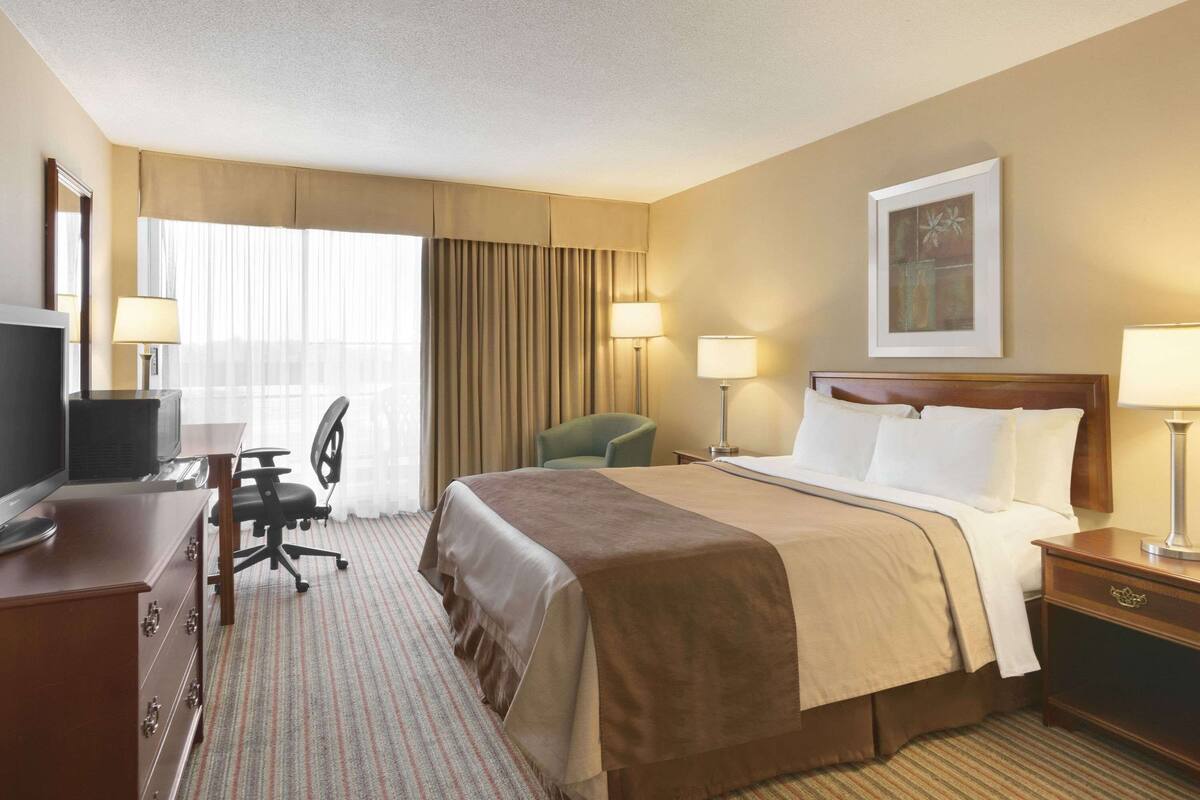 Une chambre d’hôtel comprenant un lit, un bureau avec un ordinateur, une chaise et un téléviseur.