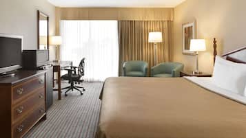 Une chambre d’hôtel avec un grand lit, un bureau avec une chaise, une télévision et deux lampes.