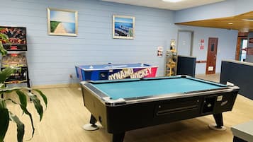 A pool table with a 'OWNAMU HOCKEY' sign, framed pictures on the wall, and a pool table in a room with wooden flooring.