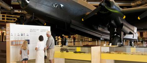 Un avión grande exhibido con paneles informativos y visitantes.