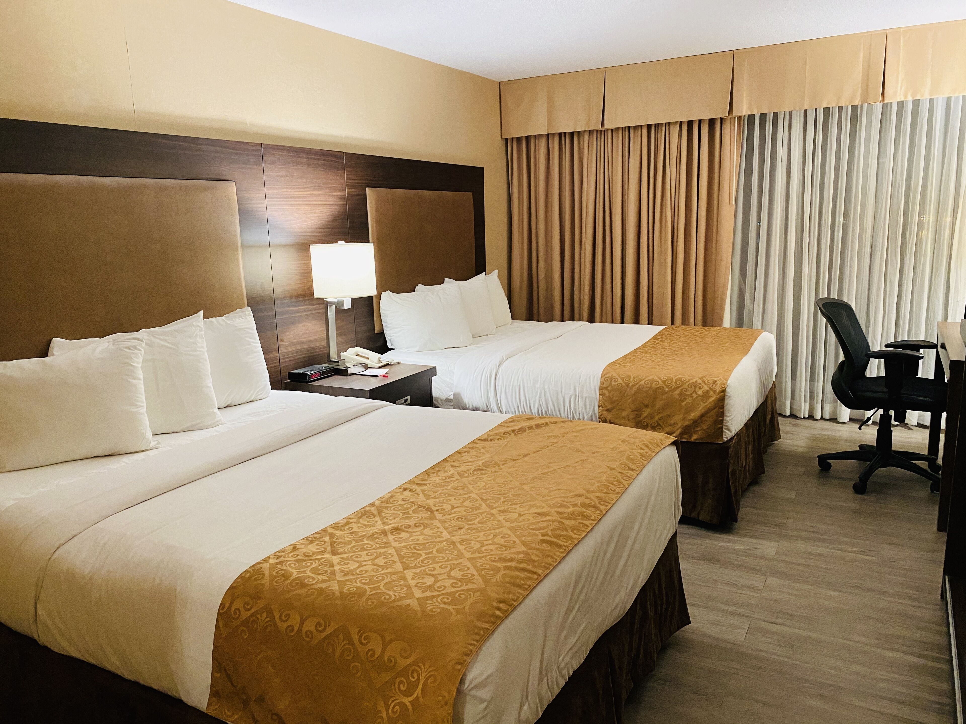 A hotel room with two beds, a desk, and a chair.