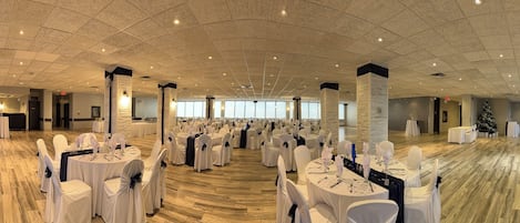 Un vaste hall doté de tables et de chaises rondes, de grandes fenêtres et d’un haut plafond.