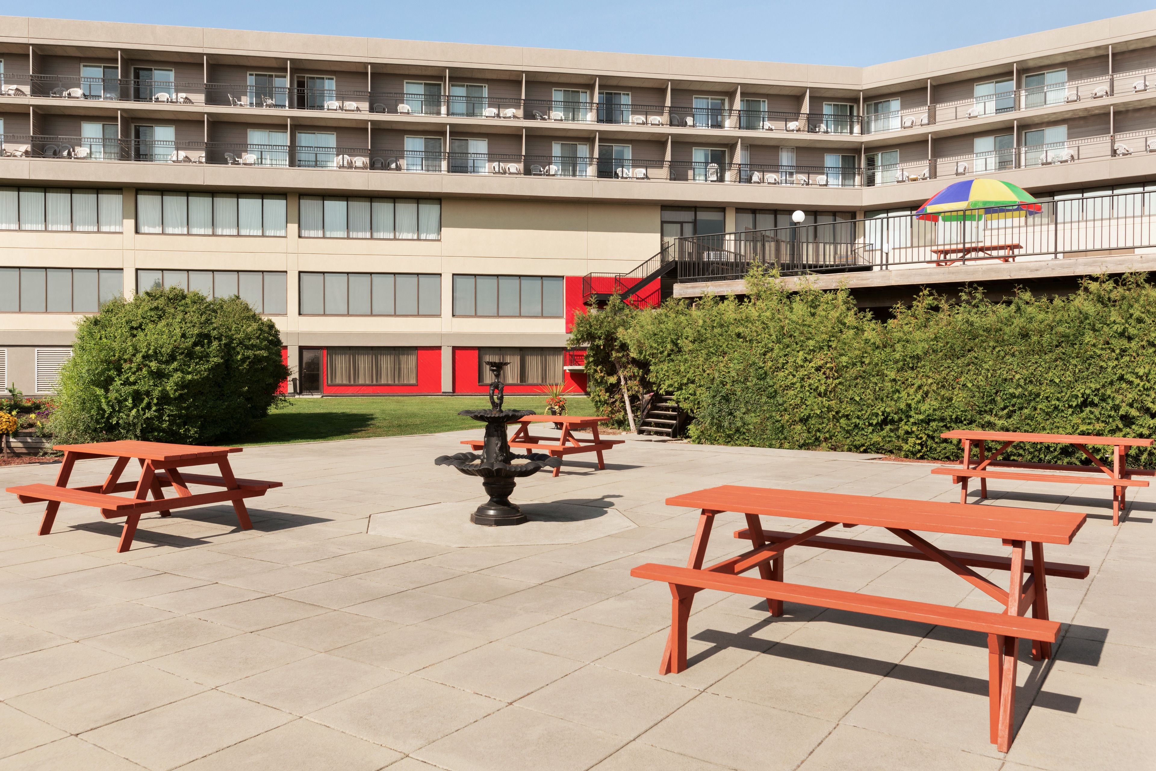 A courtyard with outdoor seating, a fountain, and a multi-story building with balconies.