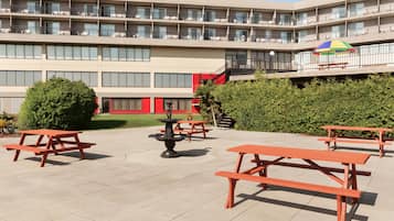 Un patio con mobiliario exterior, una fuente y un edificio de varios pisos con balcones.