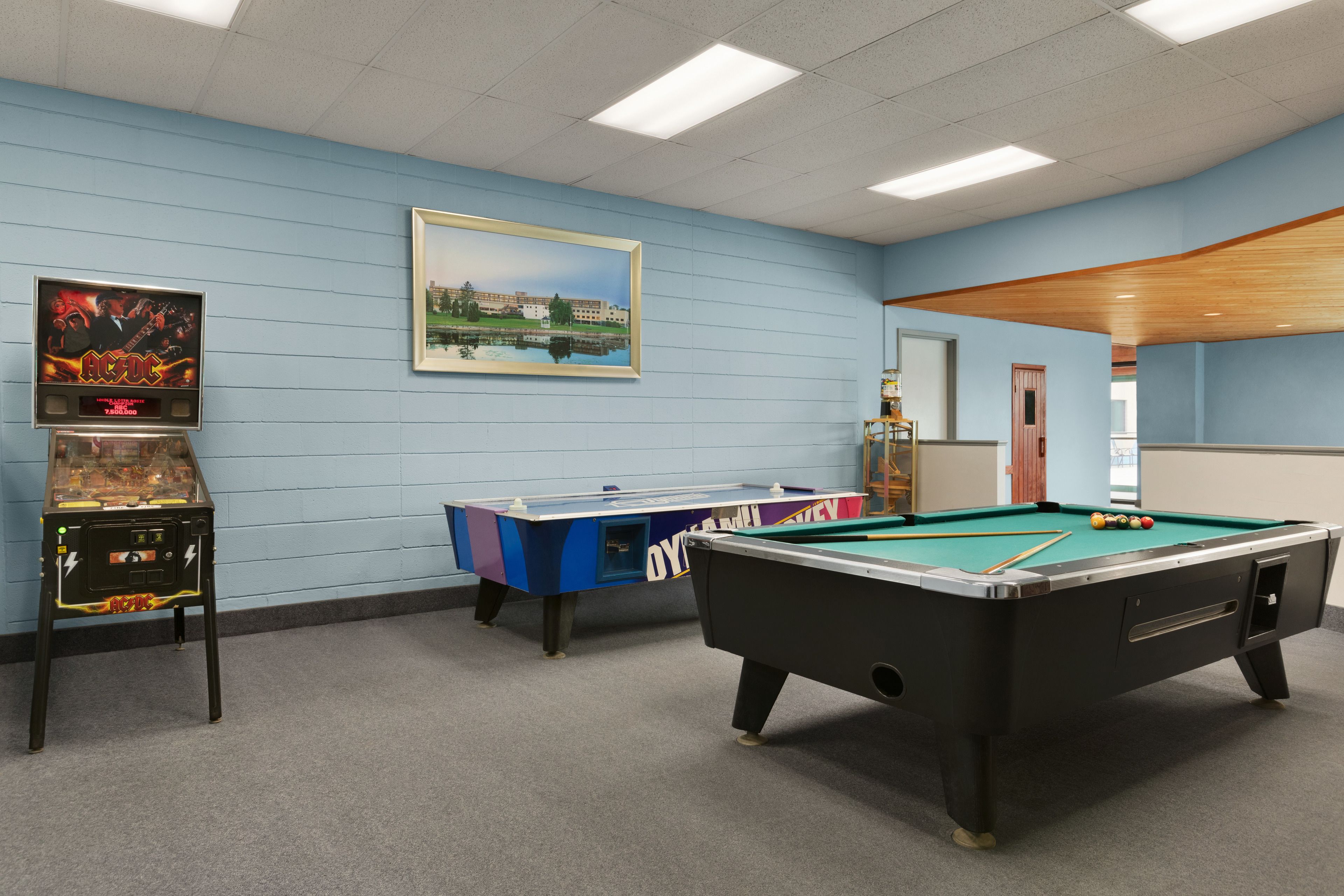 Une table de billard, une table de baby-foot et un tableau encadré accroché au mur.