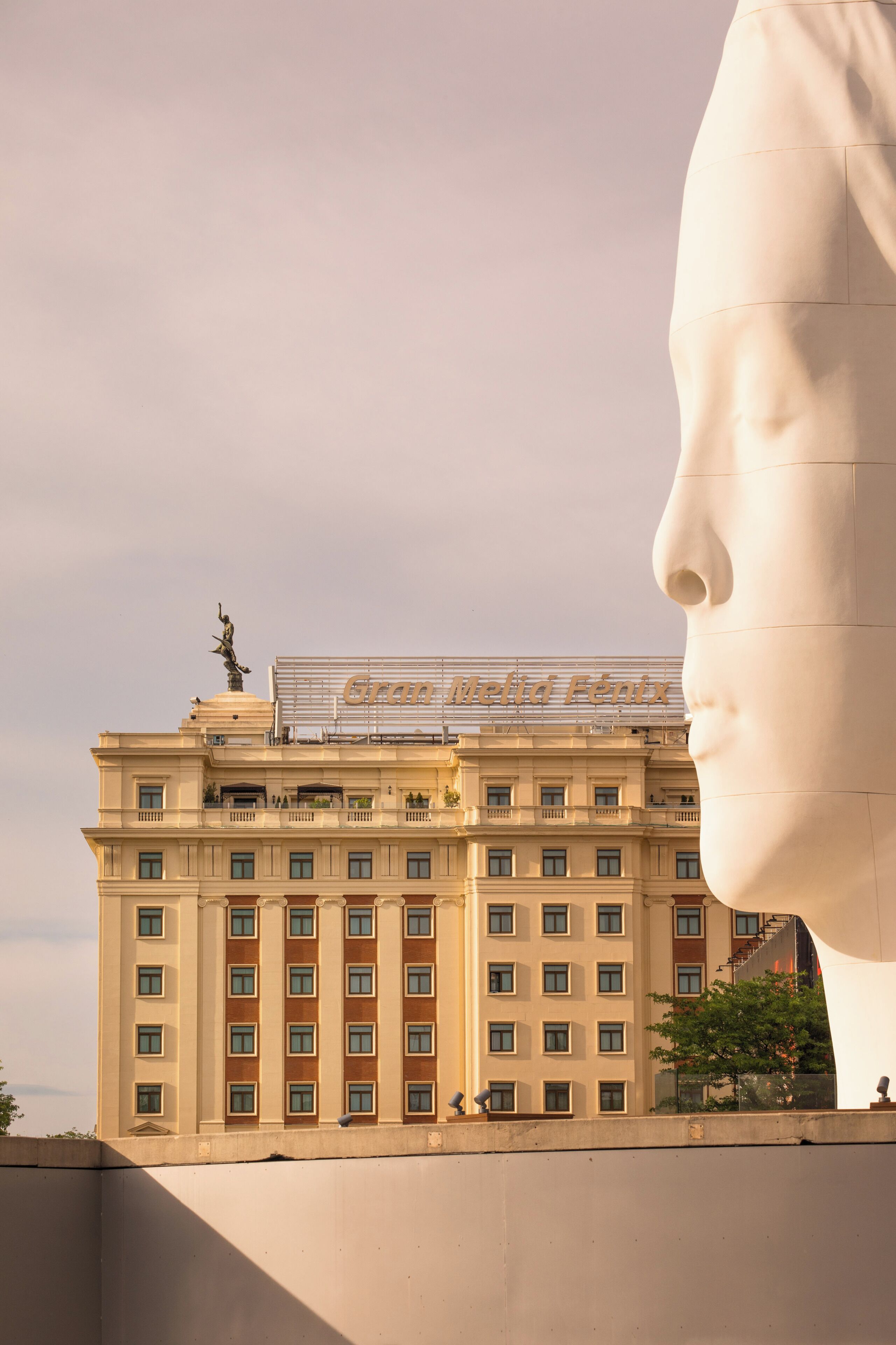 Un edificio grande con una estatua en la parte superior y una escultura blanca prominente al frente.