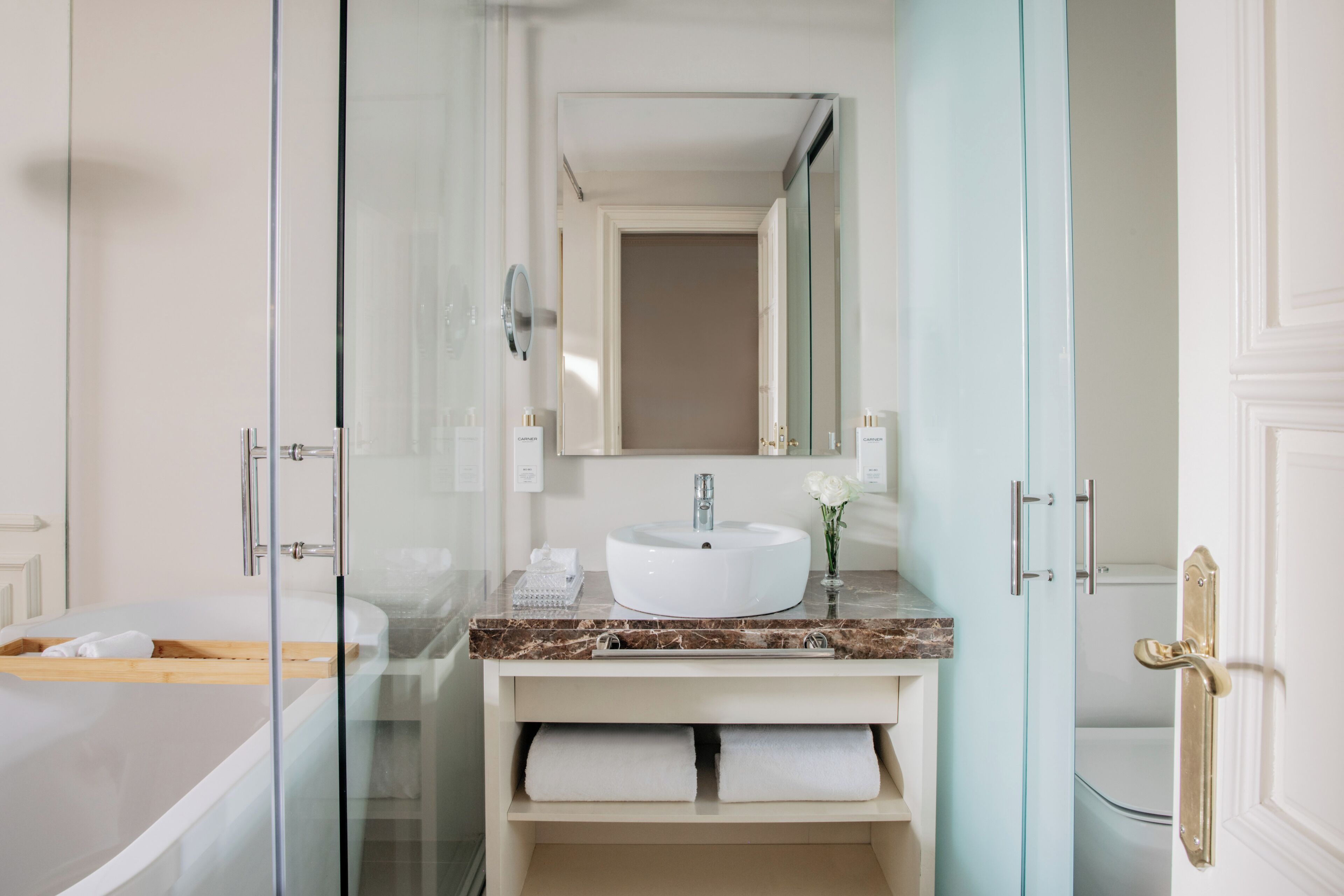 Un baño moderno con ducha envuelta en vidrio, un lavamanos blanco y una encimera de mármol.