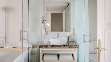 Un baño moderno con ducha envuelta en vidrio, un lavamanos blanco y una encimera de mármol.