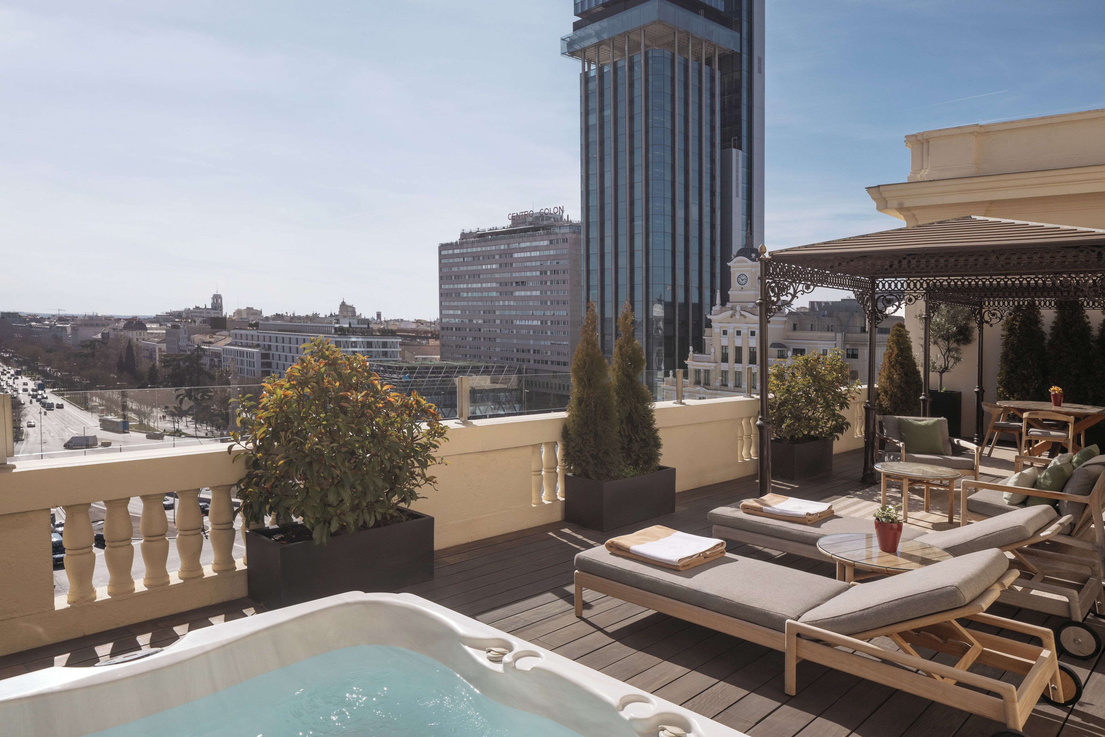 A rooftop terrace with lounge chairs, a hot tub, and potted plants.