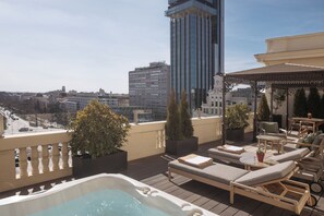 Terraza en la azotea con sillones de descanso, una bañera de hidromasaje y plantas en macetas.