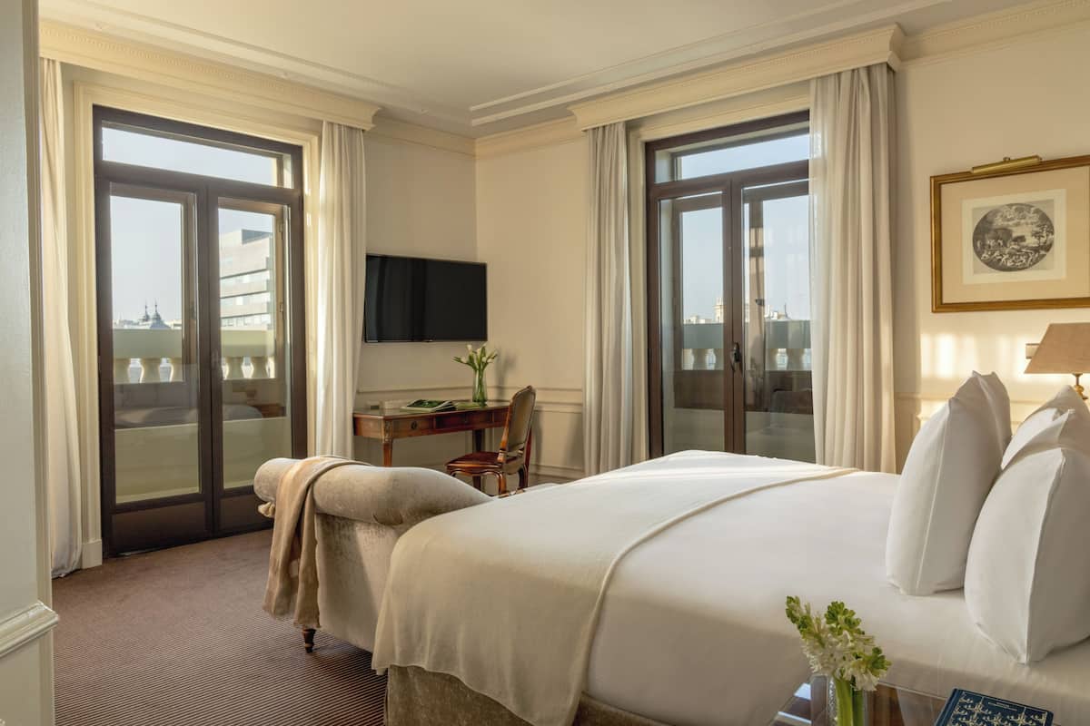Une chambre d’hôtel avec un lit, un bureau, une chaise, une télévision et une vue par la fenêtre.
