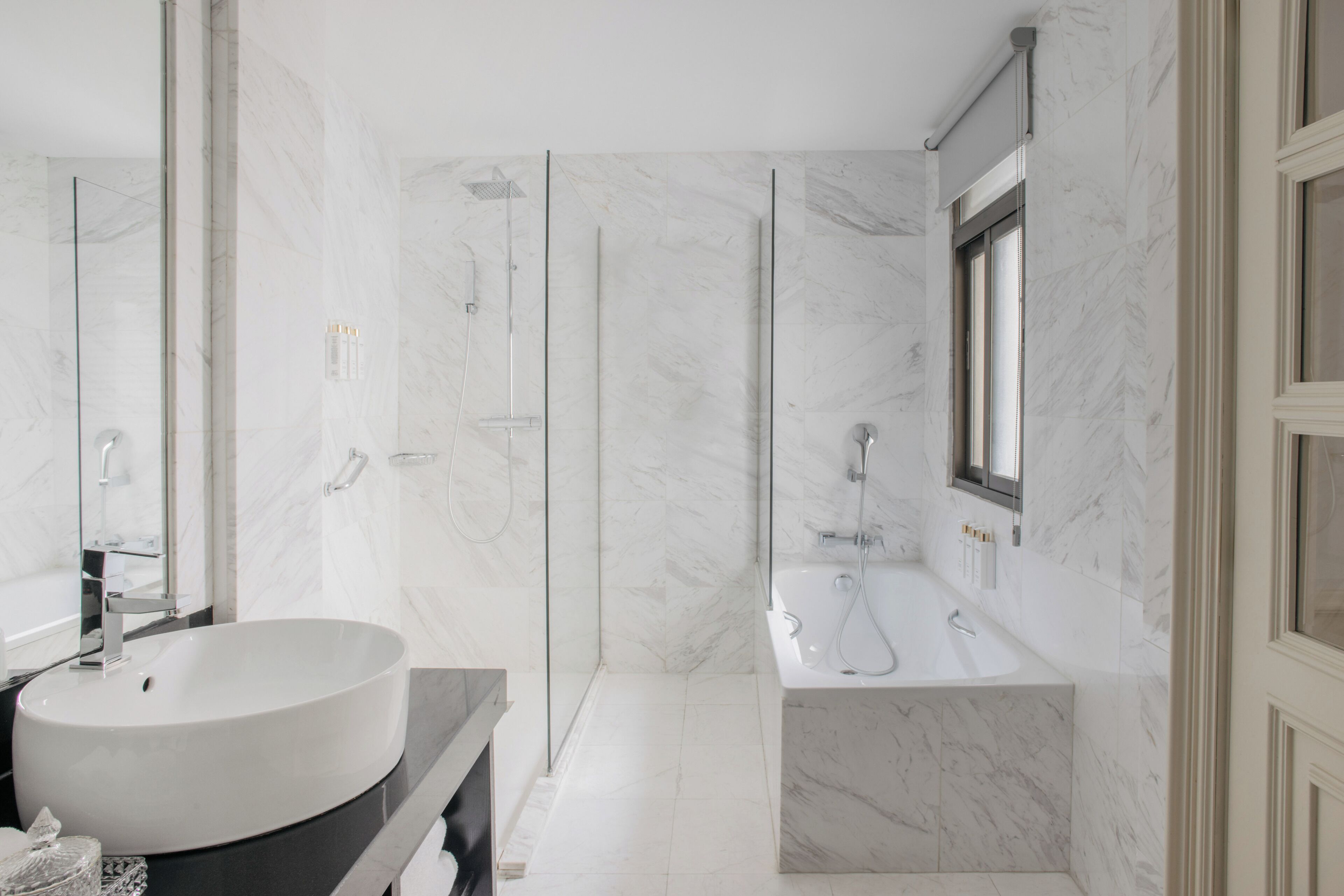 A modern bathroom with a large white sink, a bathtub, and a glass-enclosed shower.