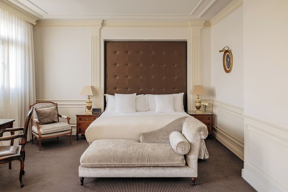 Une chambre d’hôtel avec un grand lit, deux tables de chevet, une chaise et un canapé.