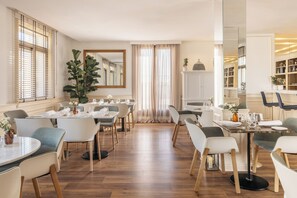 Un comedor con varias mesas y sillas, un espejo grande y una planta en maceta.