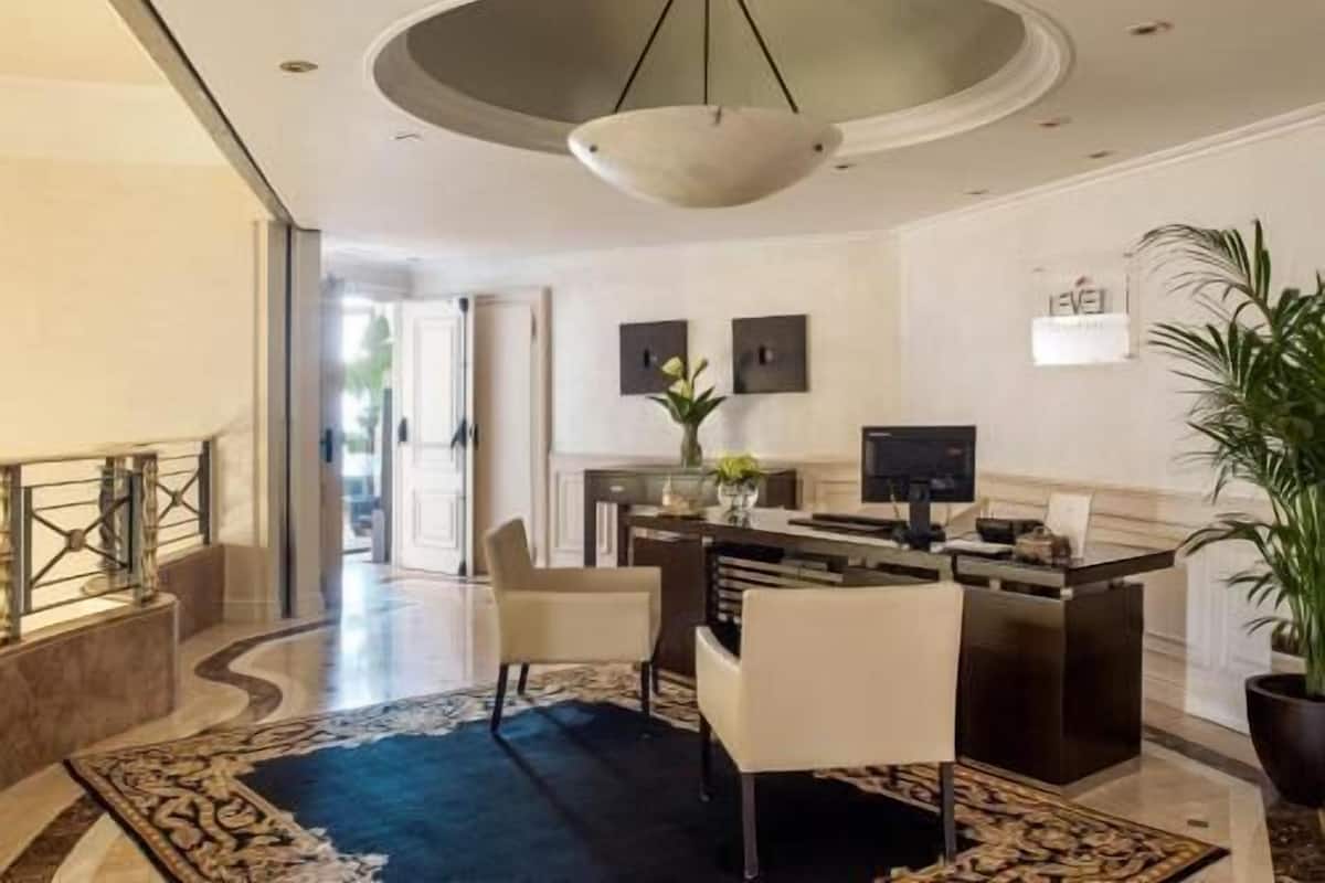 Un hall d’hôtel comprenant un comptoir d’accueil, un espace salon et un grand lustre.