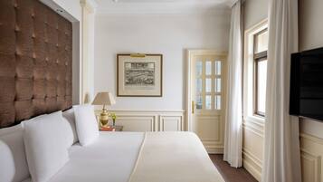 Habitación de hotel con una cama grande, televisión, un cuadro en la pared y una puerta con cortinas.