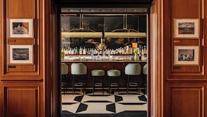 Una zona de bar con suelo de diseño blanco y negro, paneles de madera y cuadros en las paredes.