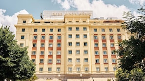 Un hotel grande de varios pisos con fachada simétrica, numerosas ventanas y un cartel llamativo en la parte superior.